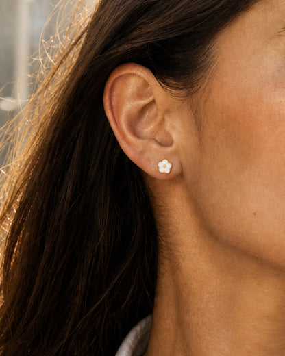 Ollijewelry white flower flat back stud earring made of surgical steel worn on a woman's ear for daily comfort