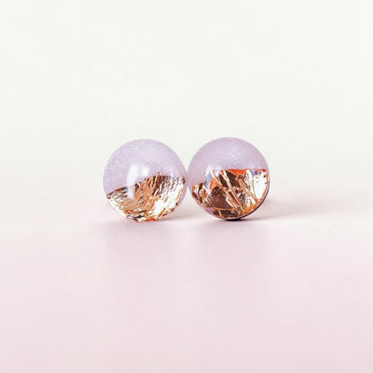 Round pale pink resin stud earrings with gold foil accents on a light background