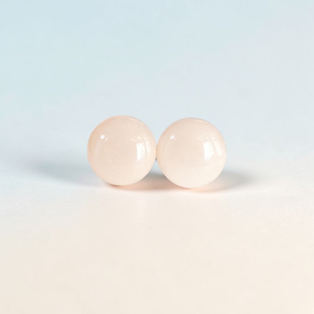 pair of round pale pink minimalist stud earrings on light background