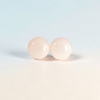 pair of round pale pink minimalist stud earrings on light background