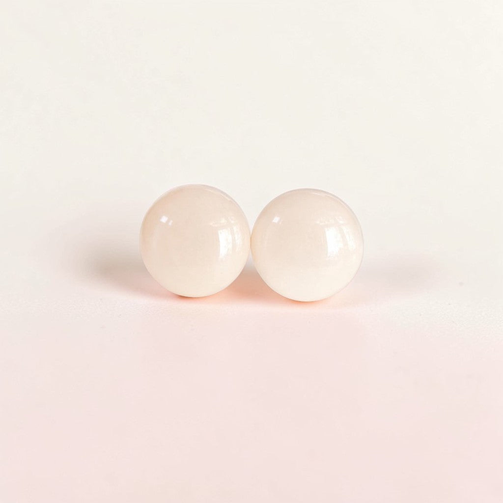 Minimalist pale pink round stud earrings on a soft neutral background